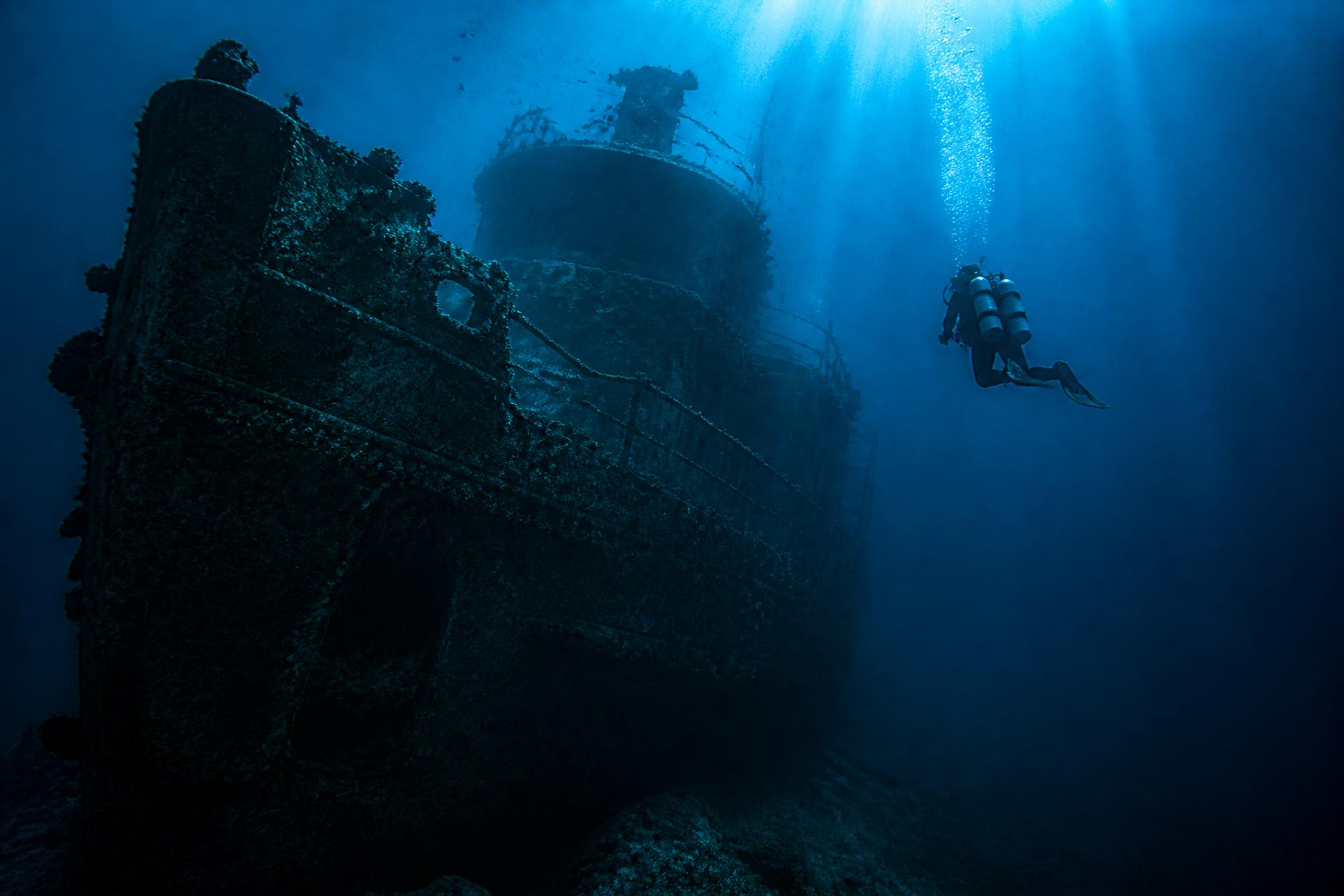 Technical diver descending on a deep shipwreck in blue water